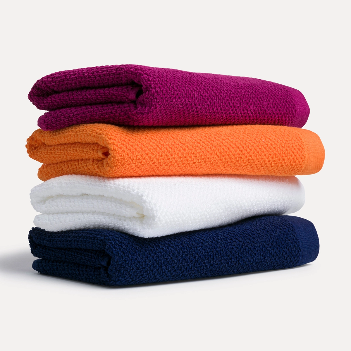 Vier BLISS-Handtücher als Stapel gelegt mit den Farben 266 Beerenrot, 106 Orange, 001 Schneeweiß und 596 Dunkles Meeresblau